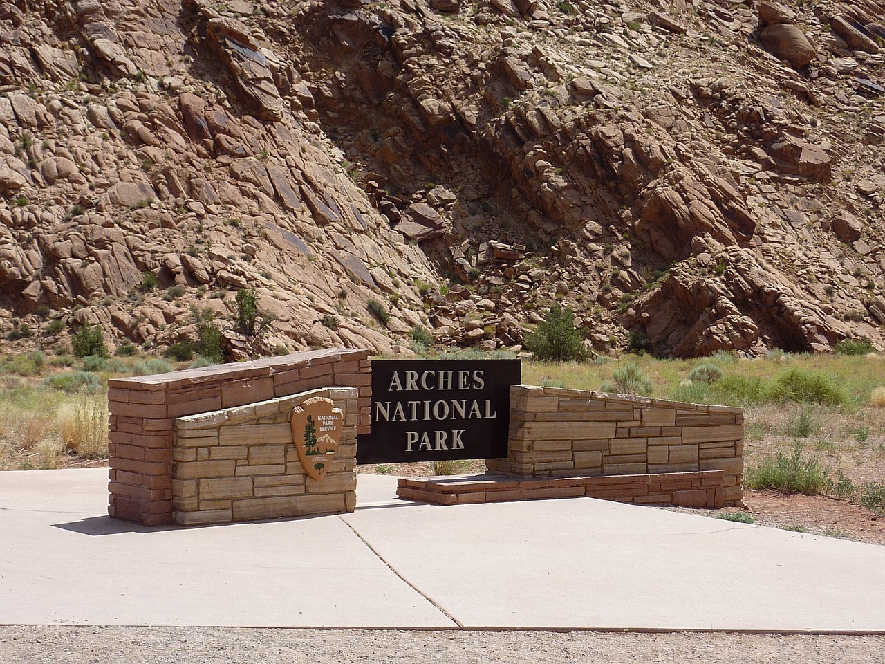 Arches National Park Entrance Sign Stone and black metal entrance sign reading Arches National Park with the National Park Service arrowhead