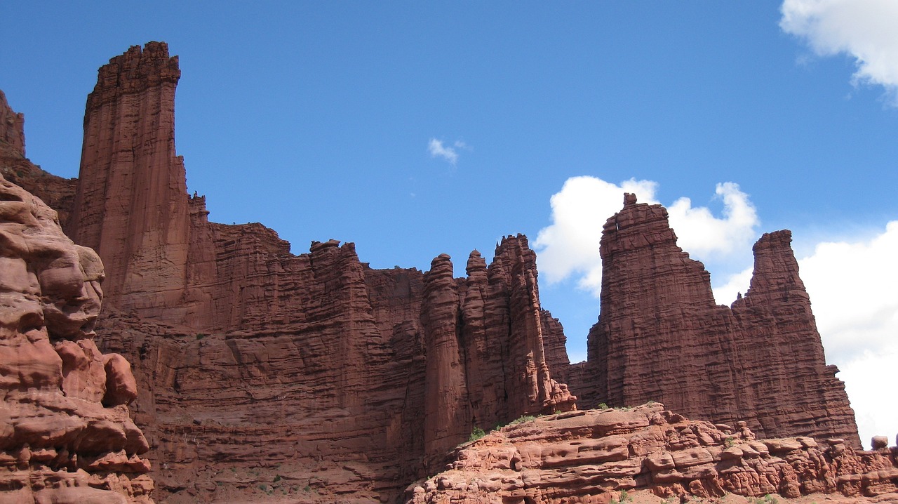 Dirt Road to Fisher Towers Red dirt road leading toward a tall rock spire and a long cliff band under a sky with cumulus clouds