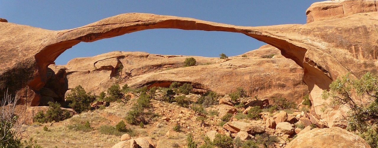 Landscape Arch, a long thin sandstone span, seen from below with blue sky showing through